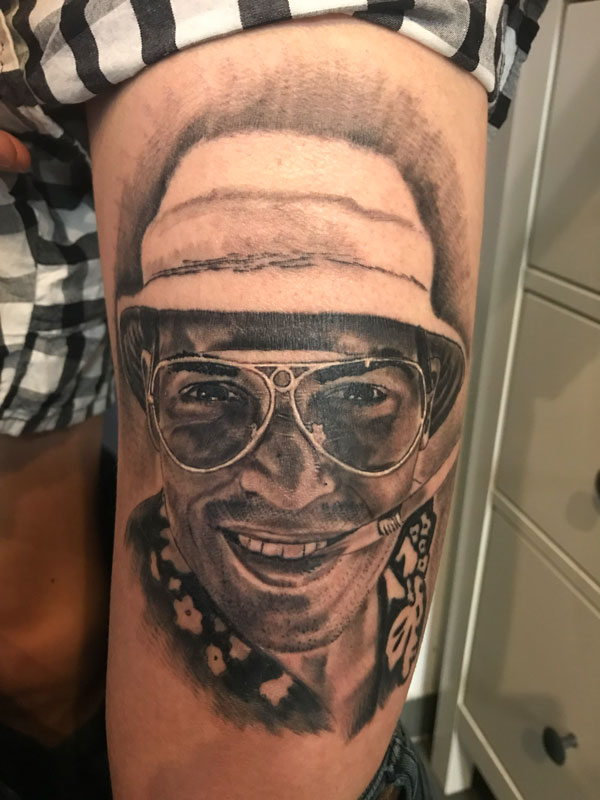 Black and Grey Cover-Up Tattoo am Oberschenkel: realistisches Porträt eines Mannes mit Brille und Fischerhut